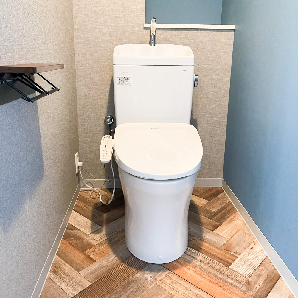 豊中市のマンションリフォーム：ヘリンボーン柄の床とブルーのアクセントクロスで、おしゃれなトイレ